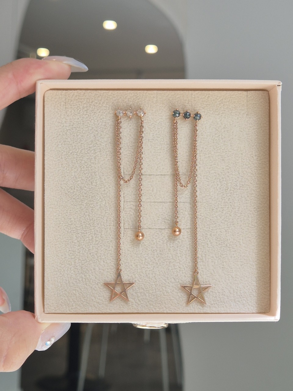 상자 안에 나란히 놓인 두 귀걸이와 세 줄의 길이 차이